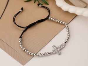 Pulsera plateada con borlas y dije de cruz